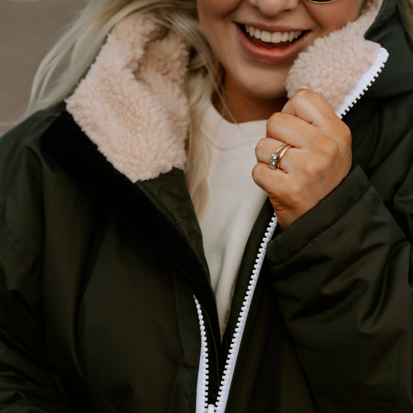 Person wearing a barbour green wild & free cobe (rain coat, changing robe, puffer coat in 1 ) with a sherpa fleece lined hood